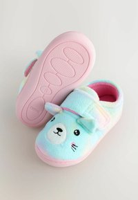 Chaussons en peluche colorés avec un dégradé pastel, ornés d'un design de visage d'ours, semelles en caoutchouc rose, et un strap auto-agrippant pour la fermeture.