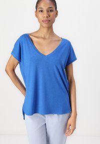 T-shirt blu a maniche corte con scollo a V, realizzato in tessuto morbido, caratterizzato da una vestibilità comoda e orlo arrotondato, abbinato a pantaloni blu chiaro.