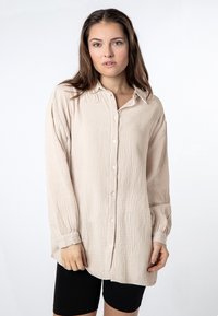 Lichtbeige button-up overhemd van textiel met een gestructureerde stof, lange mouwen en een kraag. Kenmerkt zich door een relaxte pasvorm en manchetknopen met sluitingen.