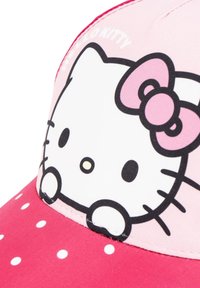 Casquette rose ornée d'un design blanc de Hello Kitty avec un nœud, des pois sur la visière et une texture de tissu lisse. Détails de couture accentués.