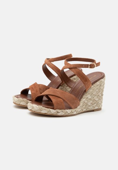 Sandales compensées en daim marron avec semelles plateforme en jute tressée et brides à la cheville avec petites boucles dorées.