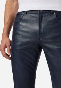 Navy leren broek met een gladde textuur, voorzien van een klassieke vijf-pocketontwerp en metalen hardware-accenten. Close-up van de taille.