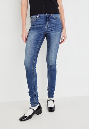 Smarte jeans i medium vask denim med en litt falmet tekstur. Har fem lommer og kontrasterende sømmer. Bært med svarte Mary Jane-sko.