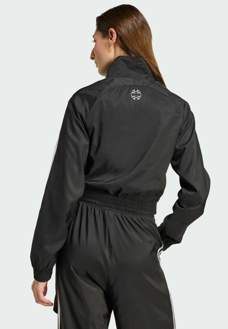 Giacca nera con colletto alto e polsini elasticizzati, caratterizzata da una vestibilità slim e un dettaglio logo sul retro, mostrata da una vista posteriore.