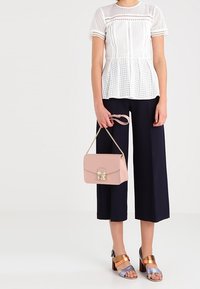 Bílý krajkový peplum top, námořnické culottes, růžová kabelka se zlatým zapínáním a sandály s barevnými blokovými podpatky a bronzovými a stříbrnými popruhy.