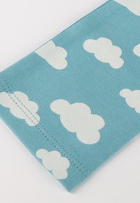 Blue fabric with a pattern of white cartoon-style clouds and visible straight stitching along the edge.