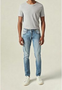 Vaaleanharmaa lyhythihainen t-paita yhdistettynä sinisiin farkkuihin, jotka ovat kapeaa mallia ja hieman haalistuneet, täydentäen kokonaisuuden valkoisilla tennareilla.