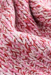 Multicolored knitted fabric with textured strands in shades of pink, red, and white, featuring a soft, fuzzy appearance and thick weave.