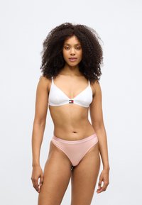 Λευκό τριγωνικό σουτιέν με λεπτές τιράντες και μικρή λεπτομέρεια λογότυπου στο κέντρο. Ταιριαστό μαγιό κάτω σε ανοιχτό ροζ χρώμα με μαλακή υφή.