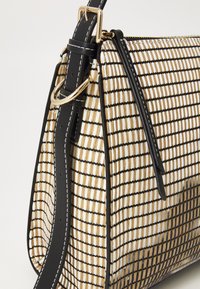 Borsa intrecciata con forma strutturata, caratterizzata da un motivo a griglia bianca e nera, dettagli beige e una tracolla nera removibile.