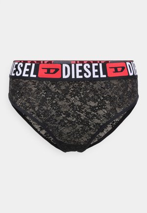 Culotte en dentelle noire avec un motif, dotée d'une ceinture élastique à logo rouge et blanc. Texture lisse avec des détails floraux.