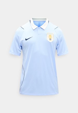 Gaiši zila īsroku futbola kreklā ar baltu apkakli, tumši zilu Nike logo kreisajā krūtī un Urugvajas futbola asociācijas emblēmu labajā krūtī.