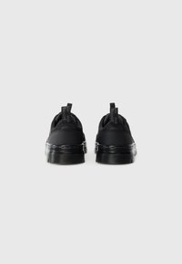 Pair of black casual shoes with thick translucent soles viewed from the back on a plain white background.