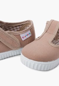 Des chaussures à enfiler en toile marron clair avec des accents élastiques sur les côtés et une semelle en caoutchouc blanche. L'intérieur possède un motif à carreaux. Étiquette de marque présente.