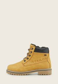Gelbe Wildleder-Ankle Boots mit schwarzen Lederakzenten, gefüttert mit Kunstfell, Schnürdesign, robuster Sohle und geprägtem Branding an der Seite.