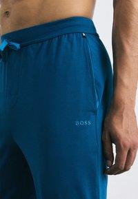 Blauwe katoenen joggingbroek met elastische tailleband en trekkoord, voorzien van zijzakken en geborduurd 'BOSS' logo in lichterblauw.