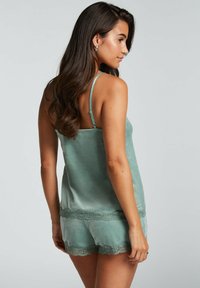 Grön satin sovset med spetsdetaljer på shorts och topp, med tunna axelband och en mjuk textur.