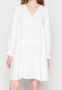 Vestido de lino blanco con escote en V, mangas largas con puños con volantes y un diseño en capas con un detalle de volante en la cintura.