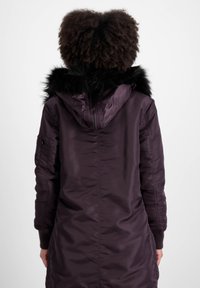 Ljubičasta parkas jakna s kapuljačom obloženom krznom, koja ima glatku vanjštinu, rebrasti rubove i zippered džep na lijevom rukavu.