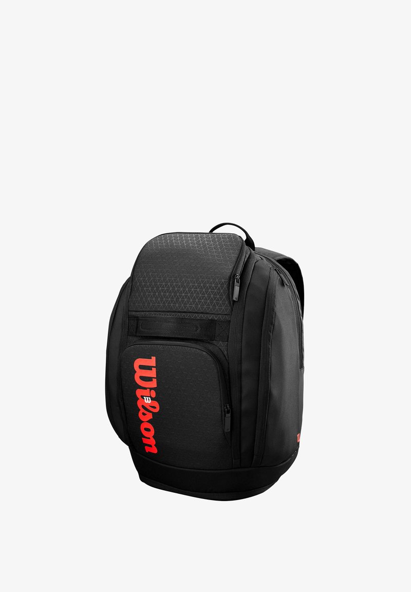 Zaino nero con texture geometrica, tasca frontale con zip e logo "Wilson" rosso ben visibile. Dotato di manico superiore e spallacci regolabili.
