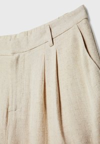 Pantalones plisados color beige claro fabricados con una tela texturizada. Presentan una cinturilla suave y sutiles detalles de costura.