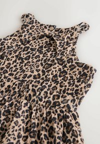 Leoparda raksta kleita ar gaisīgi bēšu fonu un melniem plankumiem, aizdare ar pogām un plecu cilpas. Izgatavota no faktūras auduma.