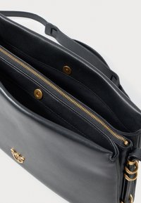 Bolsa de ombro em pele preta com fecho de correr dourado, fechos de íman, alça ajustável e pequeno emblema decorativo dourado na frente.