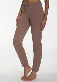 Braune lockere Sweatpants aus weichem Material, mit elastischem Bund und Kordelzug, seitlichen Taschen und gerippten Bündchen.