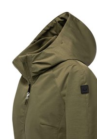 Giacca verde con cappuccio e finitura testurizzata, dotata di chiusura con cerniera frontale e una toppa nera con logo sulla manica sinistra. Design leggero e moderno.