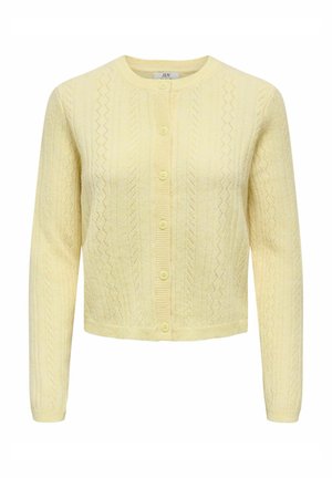 Geltonos spalvos megztinis su tekstūruotu raštu, apvalia iškirpte ir užsegimu priekyje. Turi ilgus rankovus ir trumpą kirpimą.