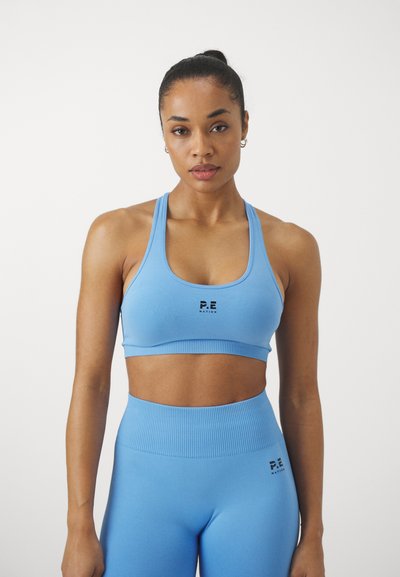 Top desportivo azul-claro e leggings de cintura alta, feitos de um material elástico com detalhes em canelado. Apresenta um logótipo preto na parte da frente.