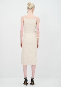 Vue arrière d'une robe midi beige avec des bretelles fines, un bodice ajusté et une taille ceinturée. Présente une coupe droite et des détails de couture minimaux.