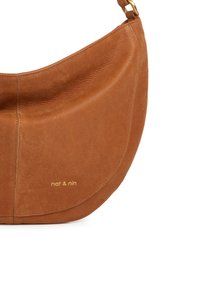 Brown leather shoulder bag with smooth texture, curved shape, and subtle stitching. Features a gold logo print 'nat & nin' on the front.