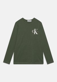 Długi rękaw, oliwkowa koszulka z bawełny, z białym nadrukiem logo na lewej piersi oraz okrągłym dekoltem. Prosta linia dołu.