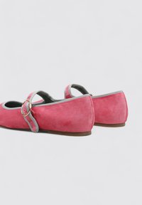 Bailarinas de ante rosa con punta redonda, ribete gris y una correa con hebilla lateral. Suela plana con textura mínima.
