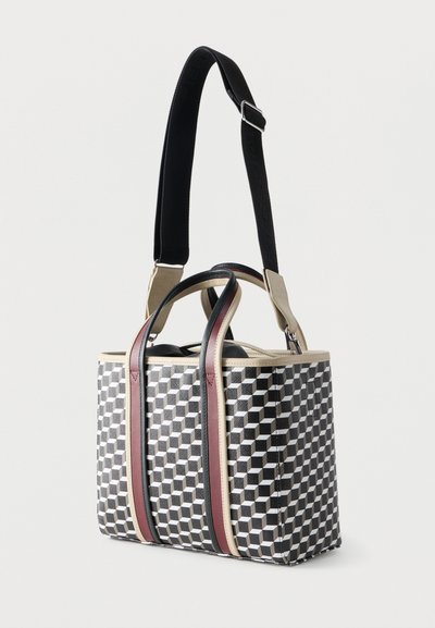 Ορθογώνια τσάντα tote με μοτίβο από κύβους σε μαύρο, άσπρο και γκρι, μπεζ περιθώριο, δύο κοντές λαβές με μαύρες και καφέ λεπτομέρειες, και μακρύ ρυθμιζόμενο μαύρο λουρί.