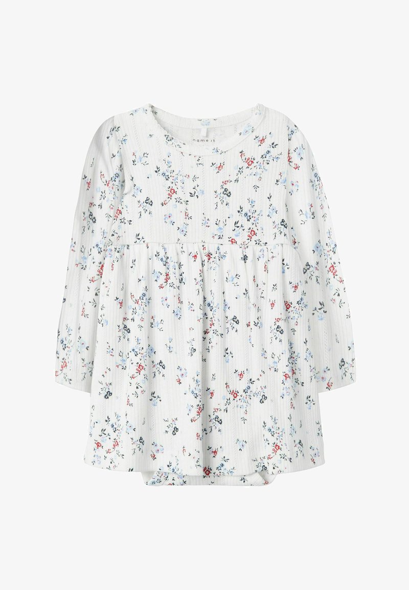 Vit långärmad topp med ett blommönster i blå och röda nyanser, en textuerad tyg och en rynkad midja för en lös passform.