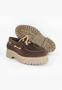 Scarpe in suede marrone con una spessa suola di gomma beige, punta arrotondata e lacci color sabbia; presenta occhielli e cuciture decorative. Suola con battistrada.