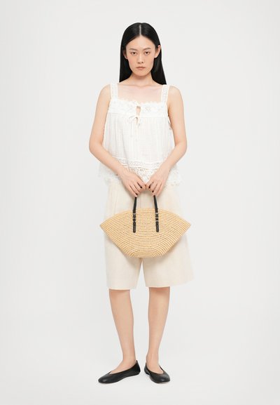 White, textured top with lace trim; beige shorts; straw handbag with black handles; black flats. Simple, light, and casual summer outfit.