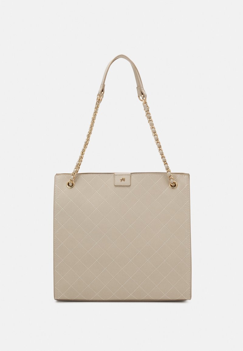 Sac à main beige matelassé avec des lanières en chaîne dorée et des coussinets d'épaule en cuir sur un fond clair uni.
