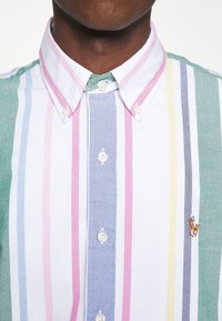 Camicia button-down a righe con strisce rosa, verdi, blu e gialle. Realizzata in cotone, con un piccolo logo ricamato sul petto.