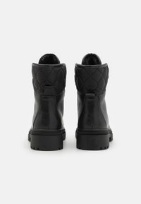 Bottines noires avec une finition en cuir lisse, un col matelassé en tissu, une semelle en caoutchouc texturée et des languettes pour un enfilage facile.