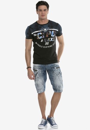 Schwarzes und blaues Grafik-T-Shirt mit Rundhalsausschnitt und kurzen Ärmeln, kombiniert mit hellblauen Bermuda-Shorts, die über Taschendetails und Nähte verfügen.