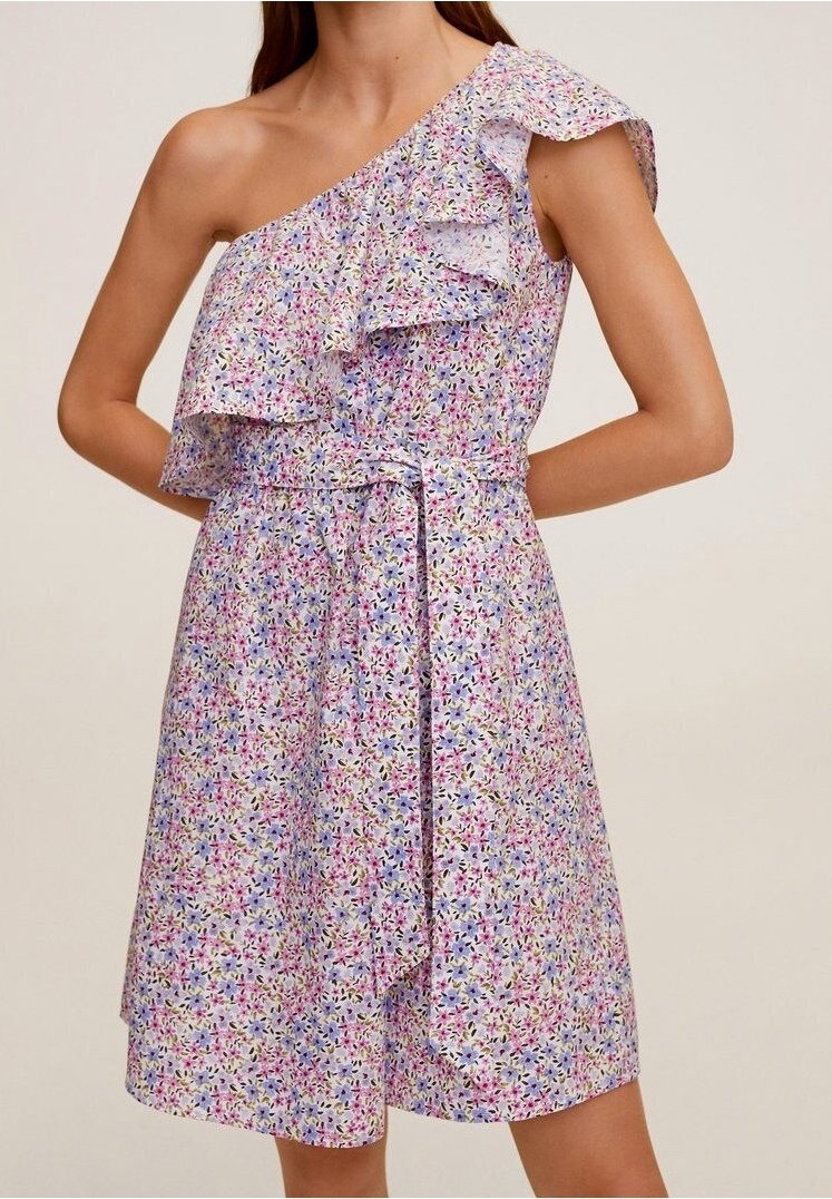 Femme portant une robe fleurie sans manches à une épaule avec un détail à volants et une ceinture en tissu nouée à la taille.