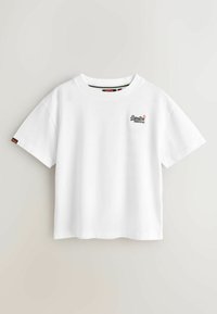 Tricou alb cu mâneci scurte, din bumbac, având un mic logo negru și roșu pe partea stângă a pieptului și o etichetă de contrast pe mânecă.