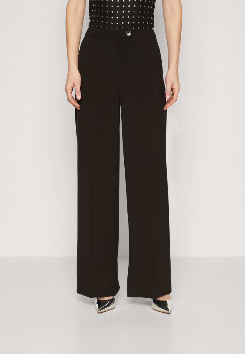 Pantalons larges noirs en tissu lisse, dotés d'une fermeture à bouton sur le devant et d'une taille structurée.