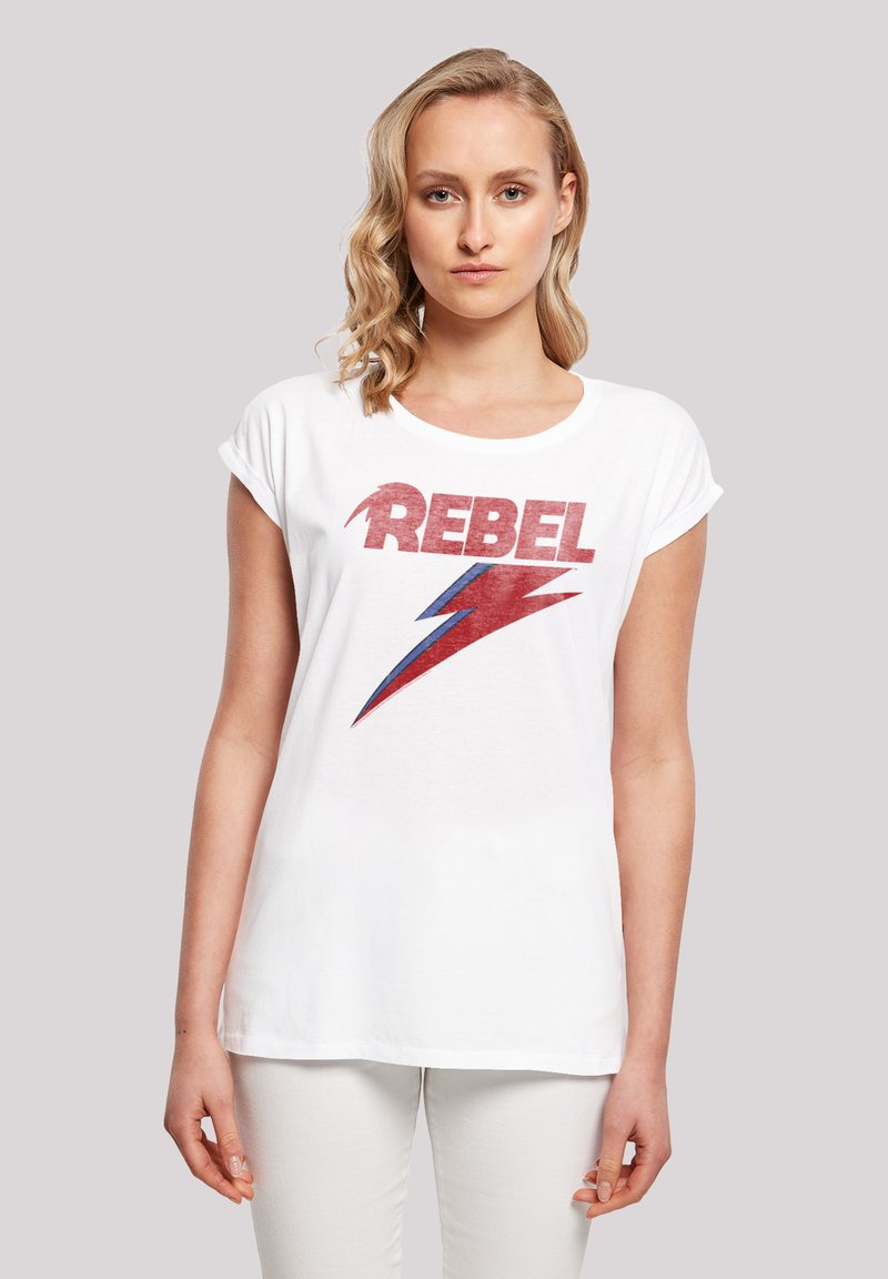 White cotton t-shirt featuring a bold red "REBEL" text with a blue lightning bolt graphic. Short sleeves and a relaxed fit.