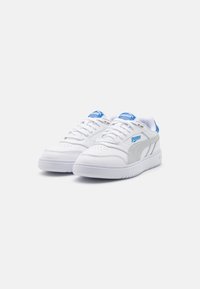 White athletic sneakers with a smooth leather upper, gray side accents, blue logo, and cushioned white sole. Features laces and perforated toe.