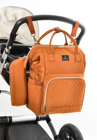 Orange kviltet stofbletaske med dobbelt håndtag og justerbare stropper, med en frontlomme med lynlås og en sidelomme, fastgjort til en babyvogn.