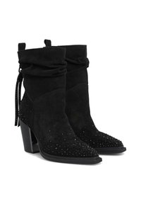Botines de ante negros con puntera afilada, parte superior suelta, acentos decorativos de remaches y tacón apilado. Presentan una lengüeta lateral y una suela elegante.